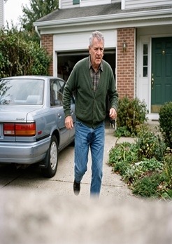 A man is walking from his car to his house with a wet spot on the front of his pants. Because, he needed to pee urgently. And, he couldn't make it in to the house.